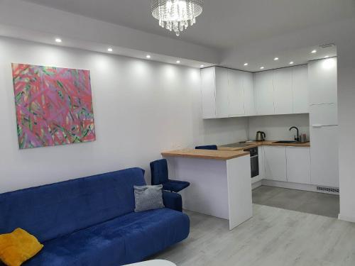a living room with a blue couch and a kitchen at Welcome Apartment in Suwałki