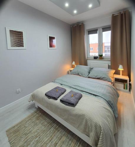 a bedroom with a bed with two towels on it at Welcome Apartment in Suwałki
