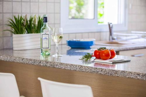 a kitchen counter with a bottle of wine and tomatoes at Villa Posidonas Three in Protaras