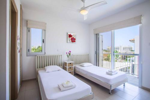 a bedroom with two beds and a window with a view at Villa Posidonas Three in Protaras