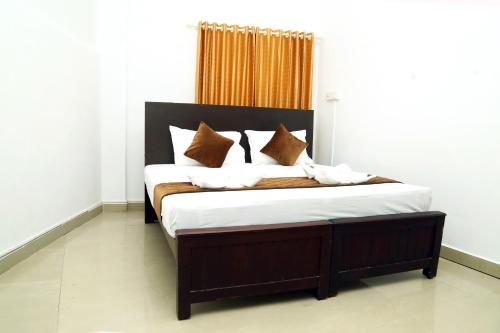 a bedroom with a large bed with brown and white pillows at AWA Residency in Cochin