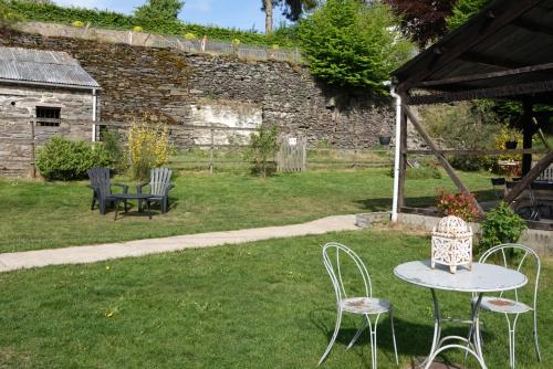 a table and chairs in a yard with a stone wall at Coeur de Boeur in Houffalize