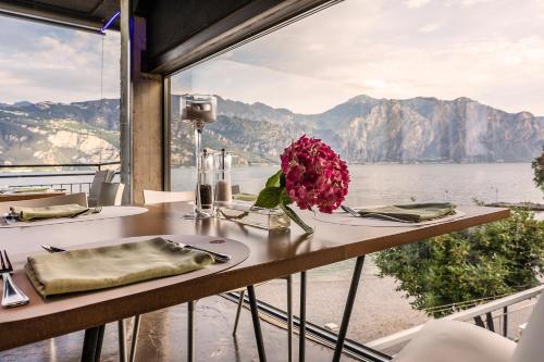 a table with a vase of flowers on a table with a view at Ambienthotel PrimaLuna 3S in Malcesine