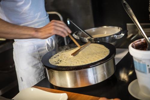 a chef preparing food in a pot in a kitchen at Ambienthotel PrimaLuna 3S in Malcesine