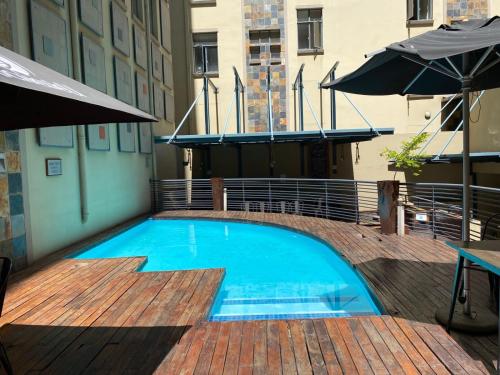 a large blue swimming pool on a balcony with umbrellas at Mapungubwe Hotel Apartments Marshalltown in Johannesburg