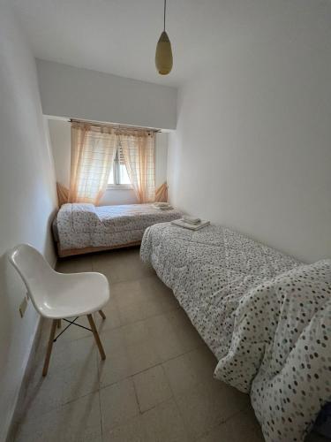 內烏肯的住宿－Departamento céntrico avenida，一间卧室设有两张床、一把椅子和一个窗户。