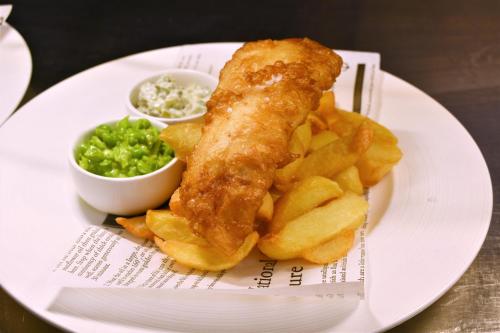 a plate of food with fish and chips and a sauce at Belgrave Sands Hotel & Spa in Torquay