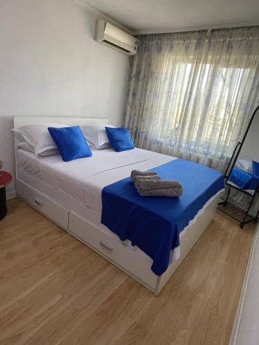 a bedroom with a bed with blue sheets and a window at Домашний уют in Shymkent