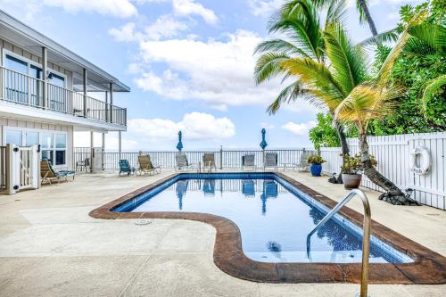 a swimming pool with a palm tree next to a house at Kona Riviera Villa #104 in Kailua-Kona