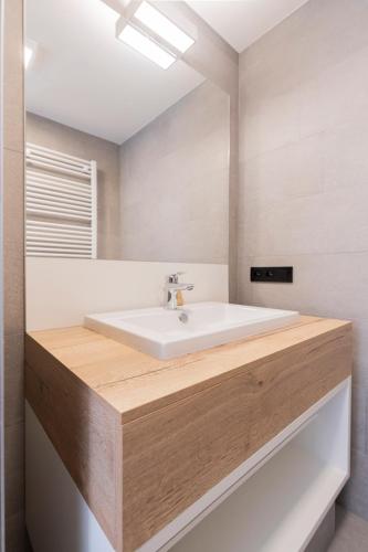 a bathroom with a white sink and a mirror at Belcasa Mar Suites & Lofts Aparthotel in Middelkerke