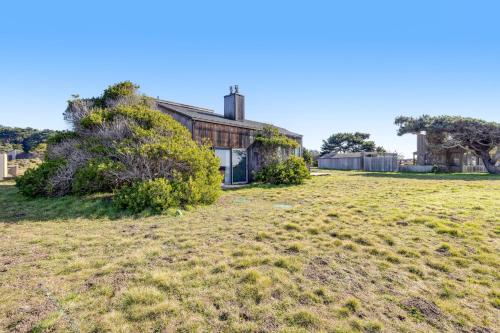 an old house with a grass field in front of it at Samson Getaway in Sea Ranch
