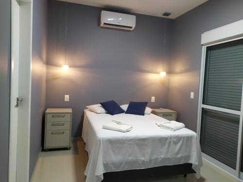 a bedroom with a white bed with blue pillows at Casa Excepcional na Praia Brava - Florianópolis in Florianópolis