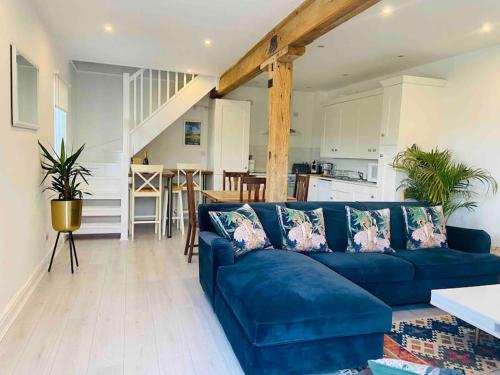 a living room with a blue couch and a kitchen at The Chaff House Country Cottage in Welsh Newton Common