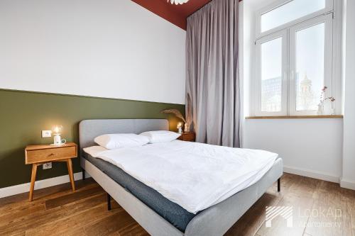 ein Schlafzimmer mit einem großen Bett und einem Fenster in der Unterkunft Polonia Residence I by LookAp in Łódź