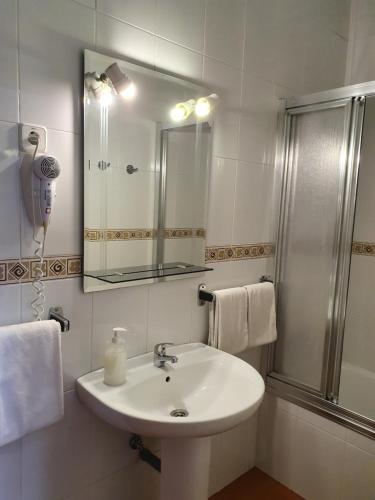 a white bathroom with a sink and a shower at Hostal Zamorán in Madrid