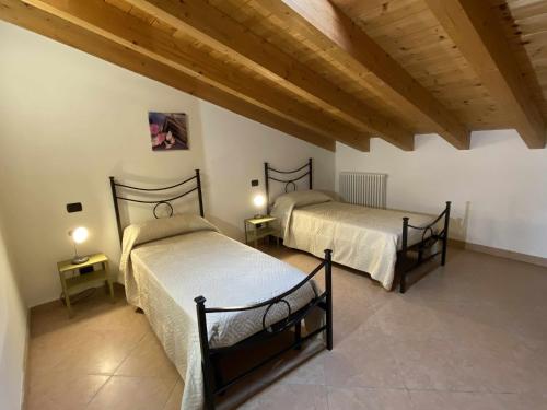 two beds in a room with wooden ceilings at La Terrazza Baldo Garda in San Zeno di Montagna