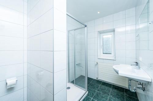 a white bathroom with a shower and a sink at Gasthaus Bauer in Grafenschlag