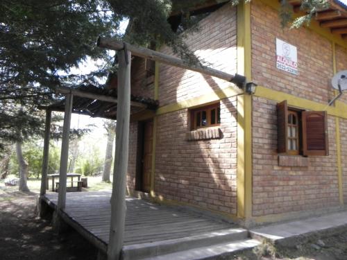 ein kleines Backsteingebäude mit einer Holzveranda in der Unterkunft Hermosa cabaña con vista a la montaña in Tunuyán