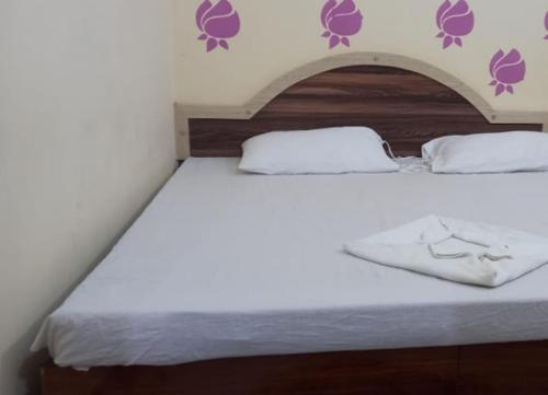 戈勒克布爾的住宿－Aman Guest House By WB Inn，卧室配有一张白色大床,墙上挂着紫色的鲜花