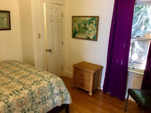 a bedroom with a bed and a window with purple curtains at Ruth House Original Craftsman PETS, walk to State st. in Santa Barbara