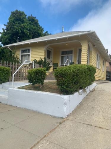 a yellow house with bushes in front of it at Ruth House Original Craftsman PETS, walk to State st. in Santa Barbara