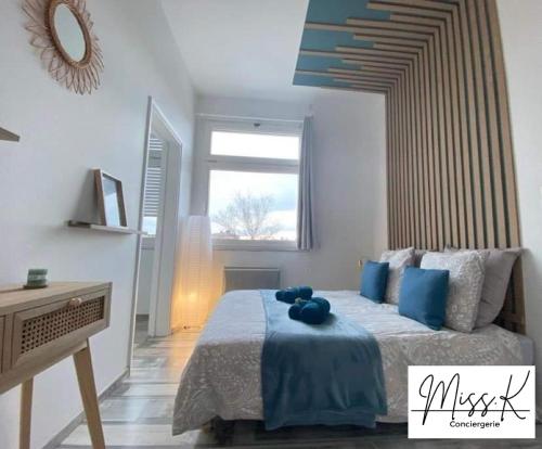 une chambre avec un lit avec des oreillers bleus dessus dans l'établissement L'Héritan de Miss.K Conciergerie, à Mâcon