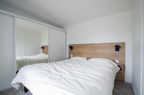 a bedroom with a white bed and a large mirror at Beau Chalet pour 4 pers - Accès piscine chauffée in Brétignolles-sur-Mer
