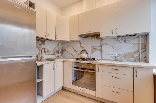 a kitchen with white cabinets and a stainless steel refrigerator at Saulės miesto širdyje „The heart of the sun city“ in Šiauliai