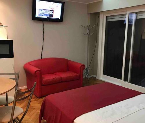 sala de estar con sofá rojo y TV en OBELISCO STUDIO en Buenos Aires