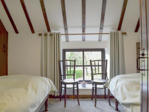 a bedroom with two chairs and a window at Oxlow End Cottage in Peak Forest