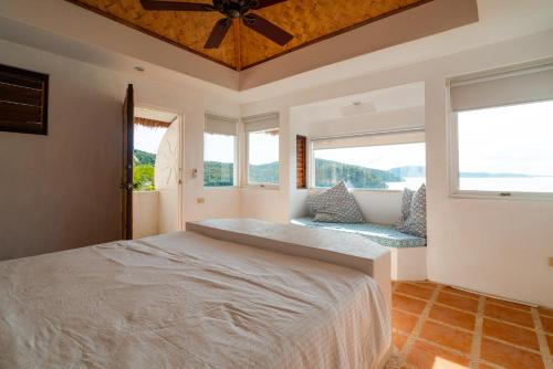 een slaapkamer met een groot bed en 2 ramen bij Marina del Sol Resort & Yacht Club in Busuanga