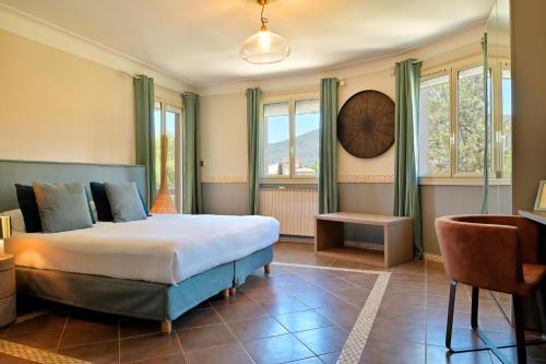 a bedroom with a bed and a desk and windows at Hotel Bartaccia in Propriano