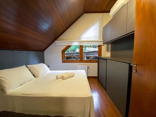 um pequeno quarto com uma cama e uma janela em LOCAR-IN GRAMADO - Orquideas 150 m da Rua Coberta em Gramado