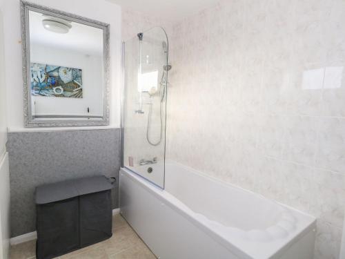 a bathroom with a tub and a shower with a mirror at Milton House in Weymouth