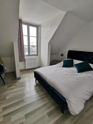 une chambre avec un grand lit blanc avec des oreillers verts dans l'établissement Comme chez vous, au Crotoy