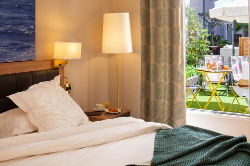 a bedroom with a bed and a window with a table at Hotel Beau Rivage in Nice