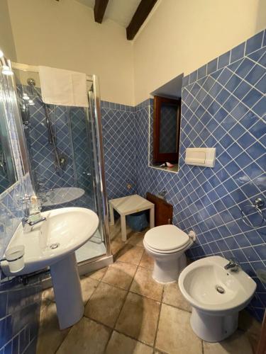 巴勒摩的住宿－Baglio Judica Apartments，蓝色瓷砖浴室设有卫生间和水槽