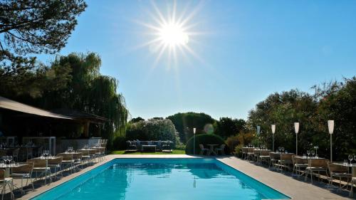 a swimming pool with chairs and the sun in the sky at Hotel Bartaccia in Propriano