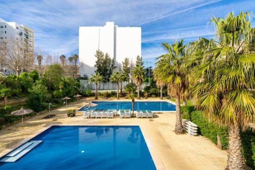 uma piscina com palmeiras e um edifício em PRAIA DA ROCHA, 4ºB Jardins da Rocha, Charming Studio, near the Sea, By IG em Portimão