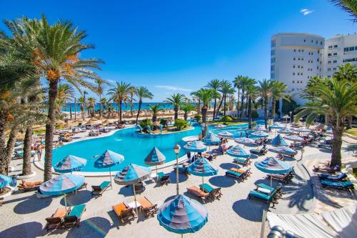 - une vue aérienne sur la piscine du complexe dotée de chaises longues et de parasols dans l'établissement Riadh Palms- Resort & Spa, à Sousse