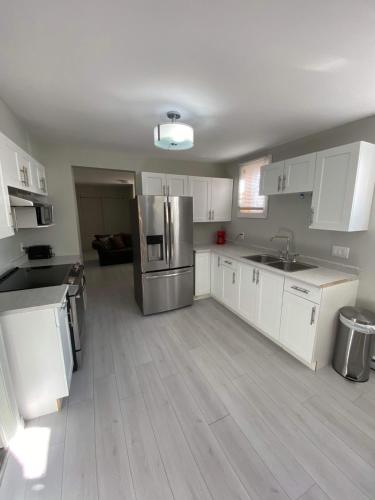 a kitchen with white cabinets and a stainless steel refrigerator at Le Cardinal in Rouyn