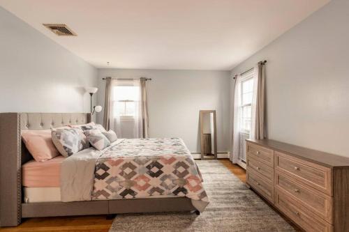 a bedroom with a bed and a dresser and windows at A Suburbia-In-The City Colonial Home in Bayonne