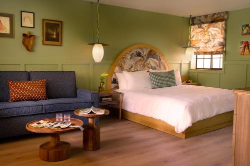 a bedroom with a bed and a couch and a table at Wayfinder Waikiki - Voted Top 10 Best Hotels in Hawaii! in Honolulu