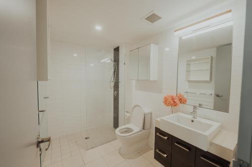 a white bathroom with a toilet and a sink at Beaufort Street Gem 1br Urban Retreat in Perth