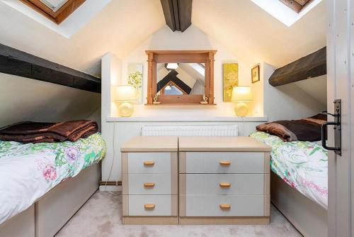 um quarto no sótão com 2 camas e um espelho em Bodfryn Cottage em Llangoed