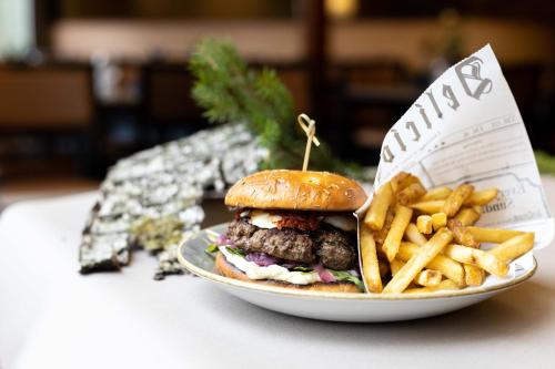 a plate with a hamburger and french fries on a table at Hotel Korpilampi in Espoo