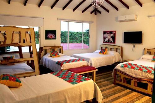 Zimmer mit 3 Betten, einem TV und einem Zimmer mit in der Unterkunft Encanto Cafetero Montenegro in Pueblo Tapao