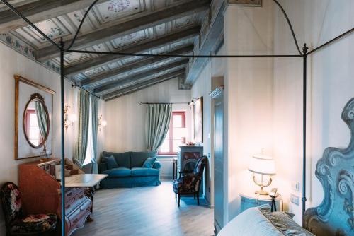 ein Schlafzimmer mit einem Bett und einem blauen Sofa in einem Zimmer in der Unterkunft Relais Villa Prato in Mombaruzzo