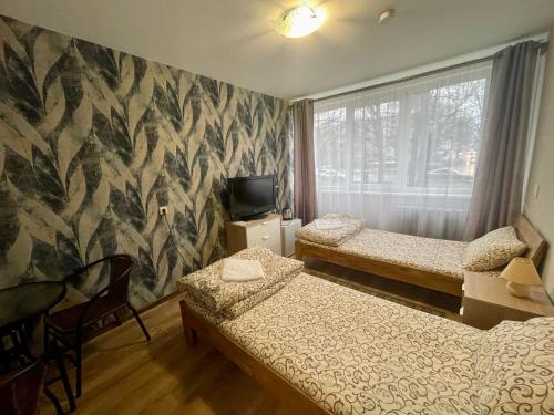 a room with two beds and a tv and a window at Savan House "Easy Kaunas" in Kaunas