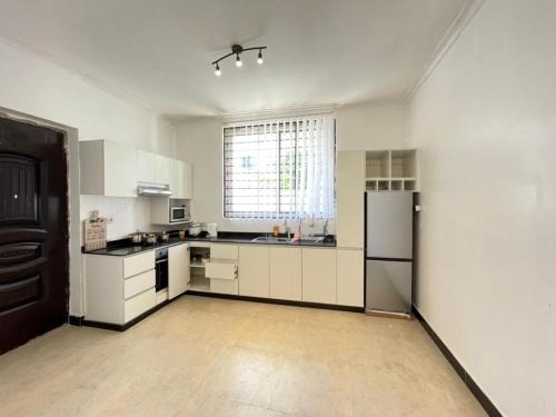 uma cozinha com armários brancos e uma grande janela em Travellers stay em Dar es Salaam